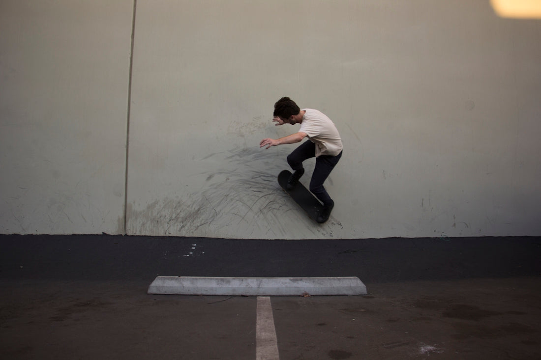 man in white shirt and black pants sitting on black skateboard