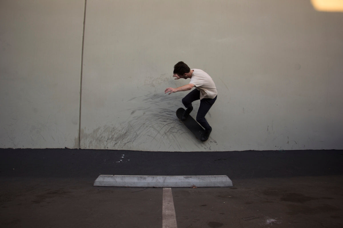 man in white shirt and black pants sitting on black skateboard