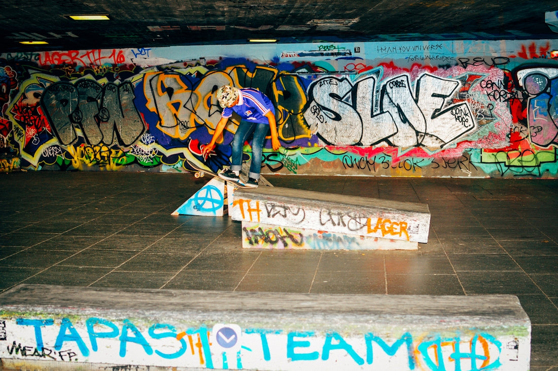 A skateboarder attempts a trick in a graffiti-covered space.