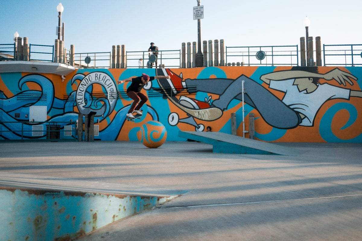 Skateboarder performs trick against colorful mural