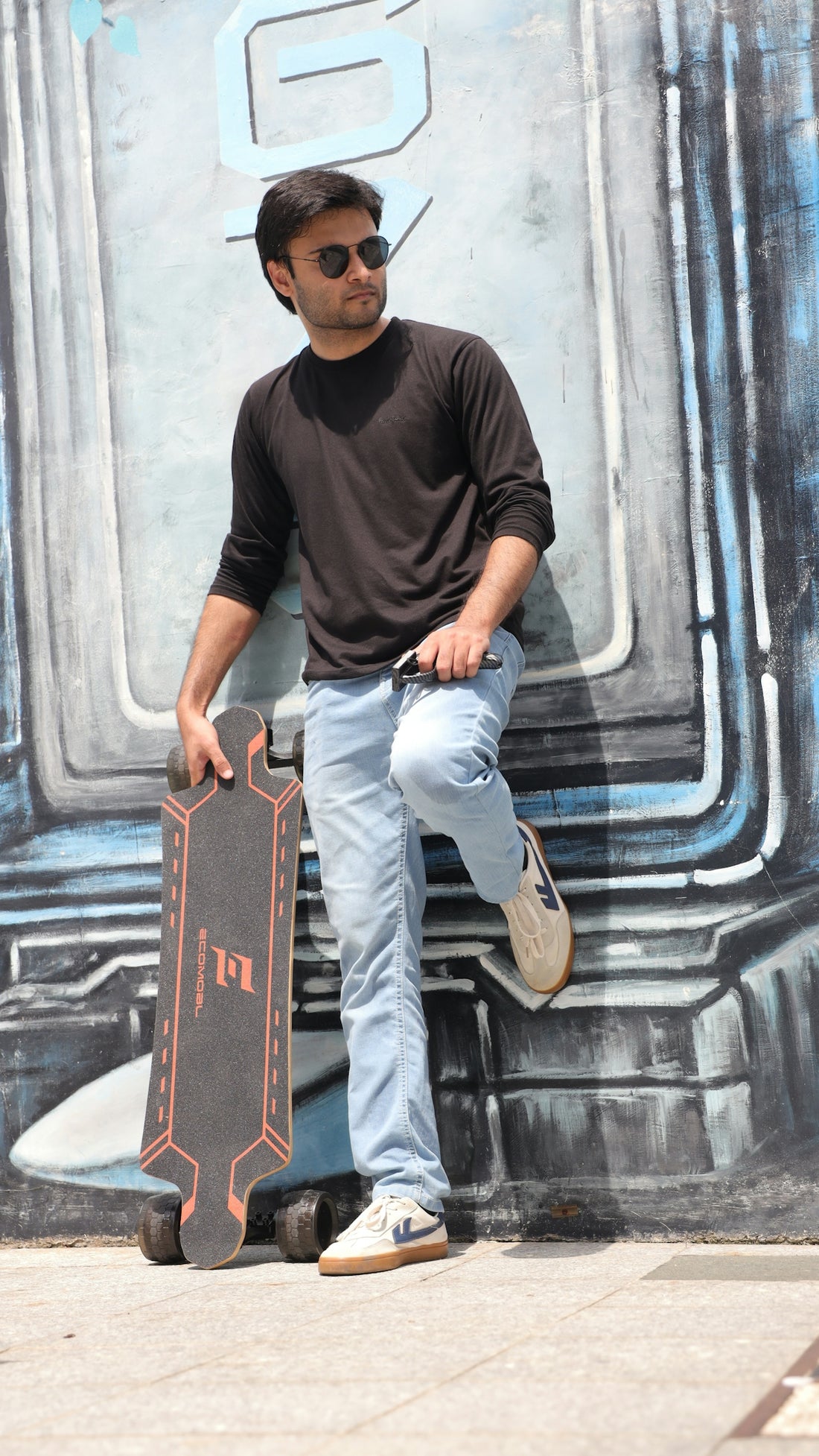 Man with skateboard leaning against graffiti wall