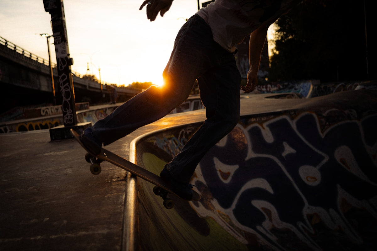 Skateboarder rides a ramp at sunset